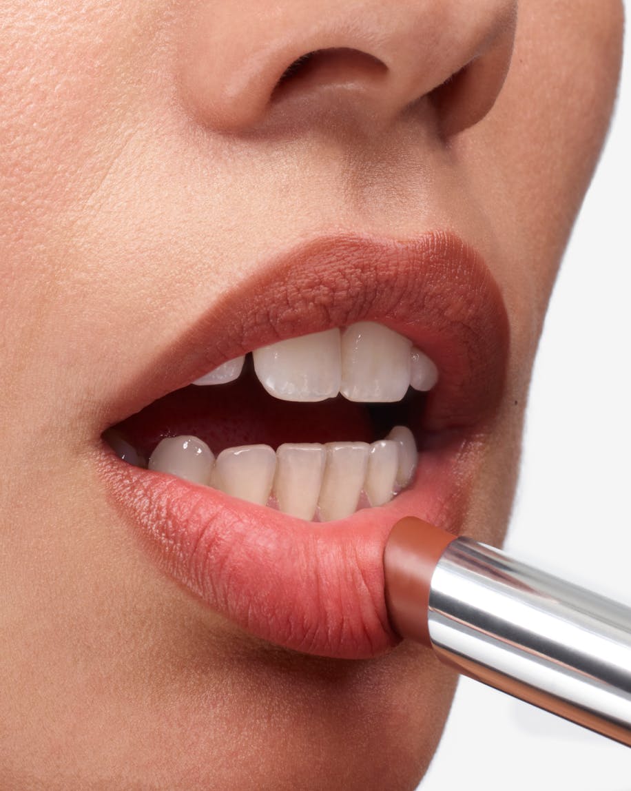 close up of model applying generation g lipstick in malt to lips